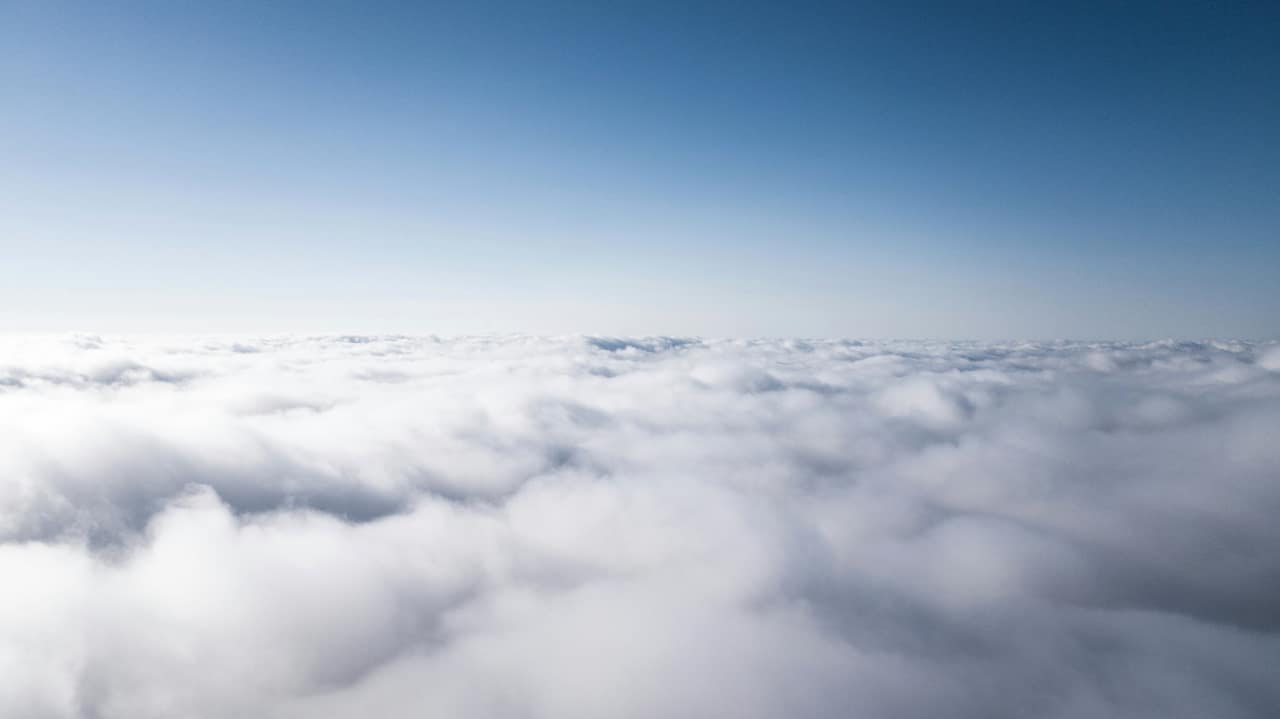 A sea of white cloud seen from above, under a clear blue sky